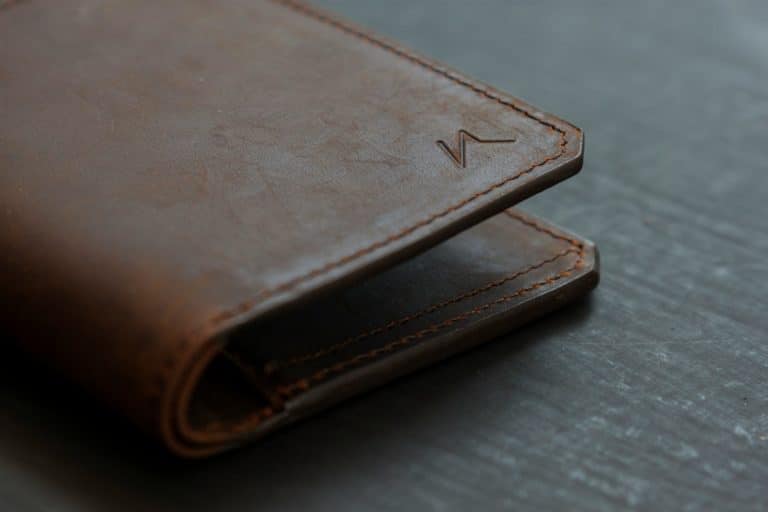 portefeuille en cuir marron sur une table en bois gris
